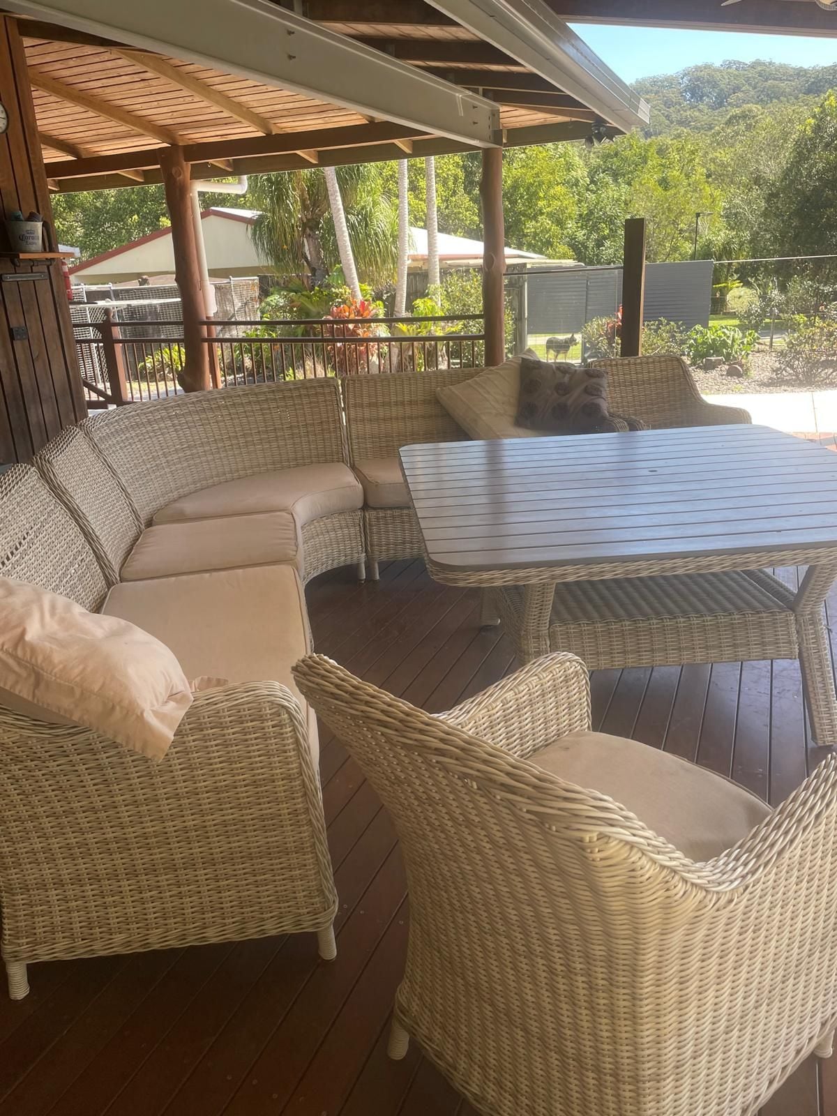 A covered outdoor seating area with wicker furniture and a table.