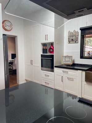 A modern kitchen with white cabinetry, a black countertop, and a stainless steel refrigerator.