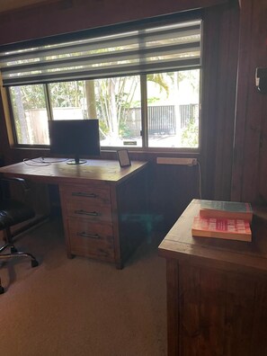 A room with a desk, a chair, a computer, and a window with blinds.