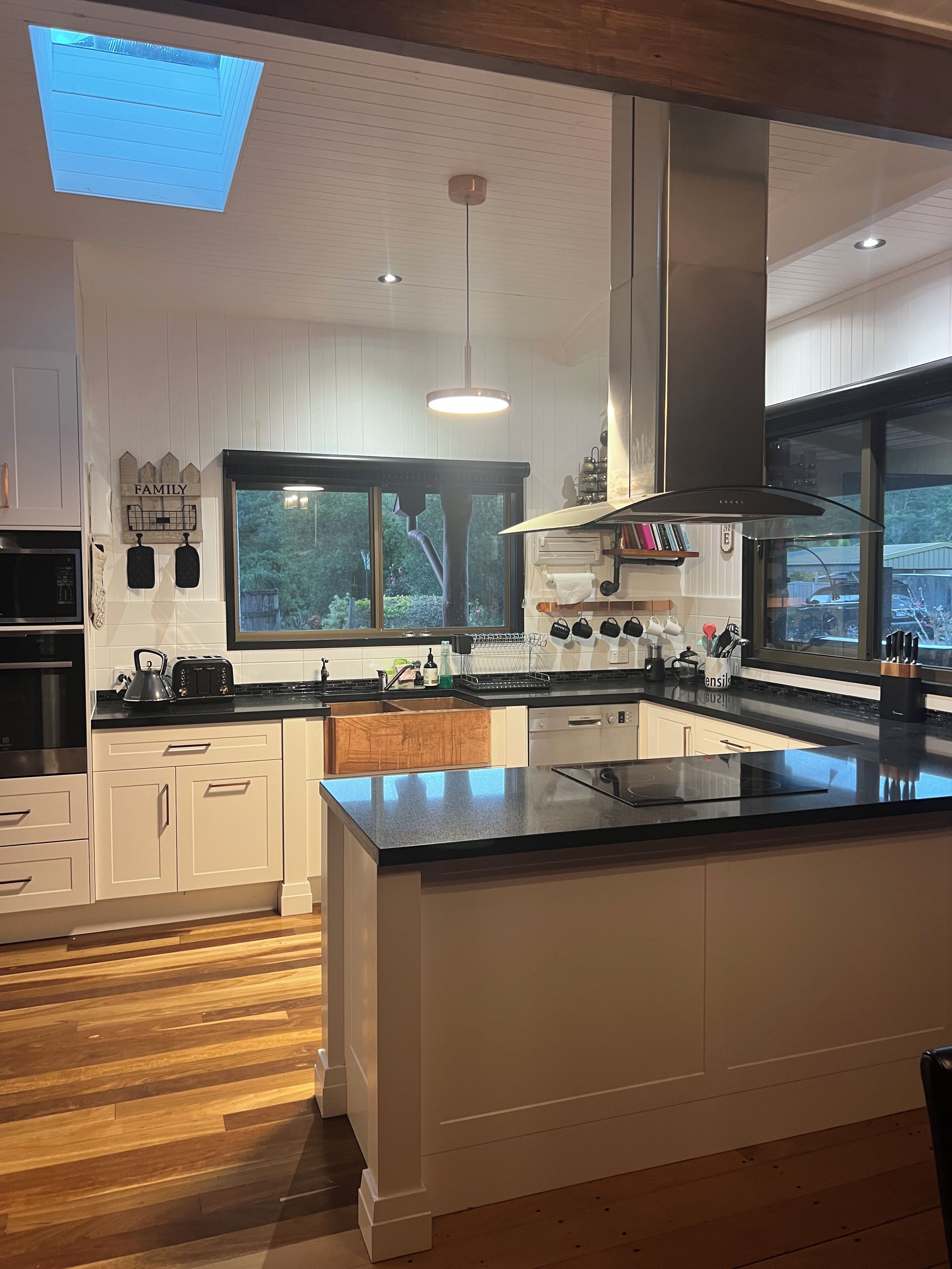 A modern kitchen with white cabinetry, a large island, and a skylight.