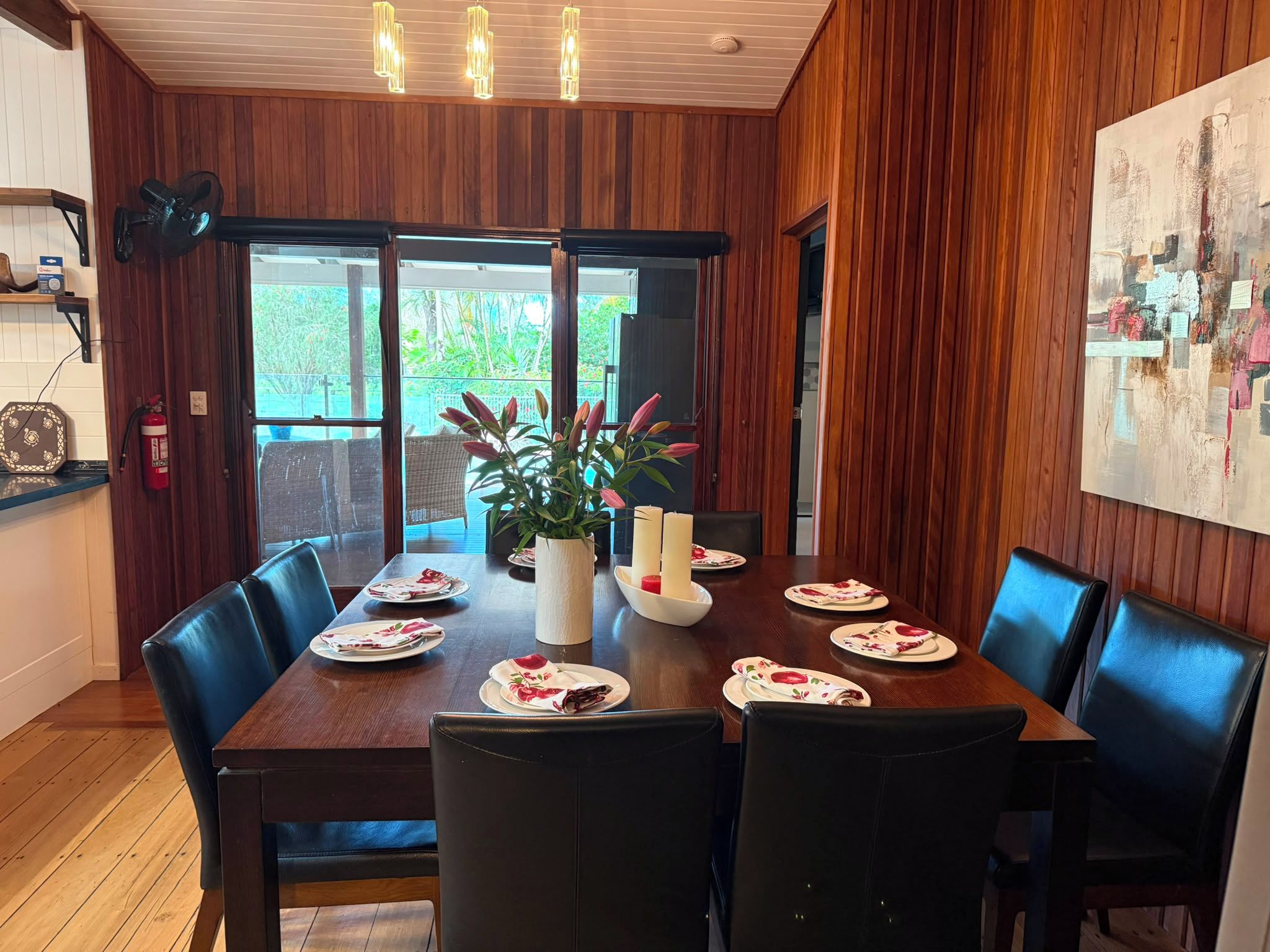 A dining area with a wooden table, black chairs, and a potted plant.