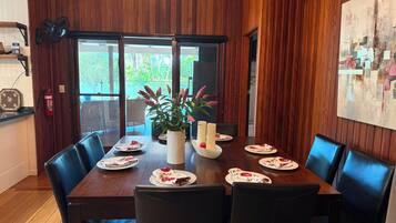 A dining area with a wooden table, black chairs, and a potted plant.