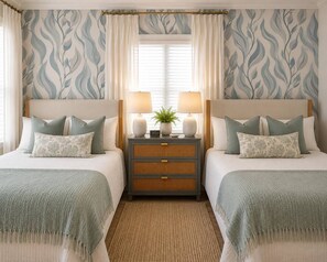 A bedroom with two beds, a nightstand with a lamp, and a window with curtains. - Summersalt Retreat• Canal Views • Walk to Dining • Pet Friendly (Gulf Shores)