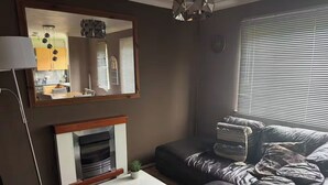 Un salon comprenant un canapé, une table basse, une cheminée, un miroir et un lampadaire.