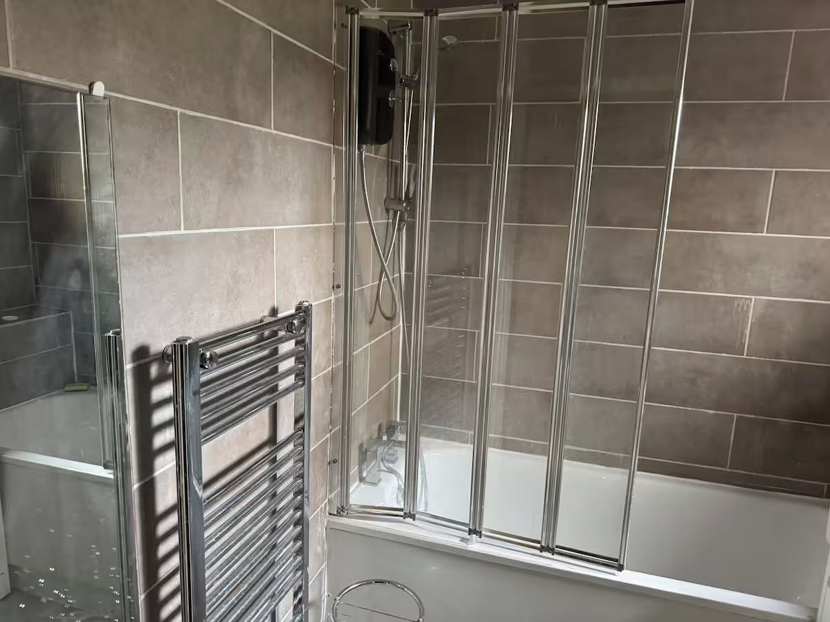 A bathroom with a glass-enclosed shower, a bathtub, and a towel rack.