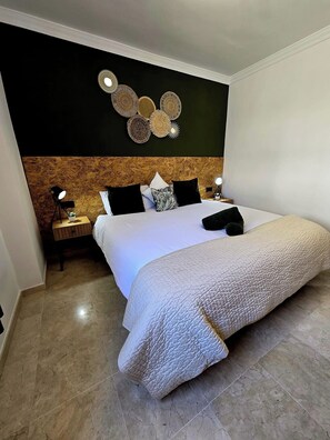 A hotel room with a bed, a nightstand, a lamp, and a wall decoration. - 3 Bed Apartment - Sleeps 6 - Pool - Parking - Golf (Mijas)
