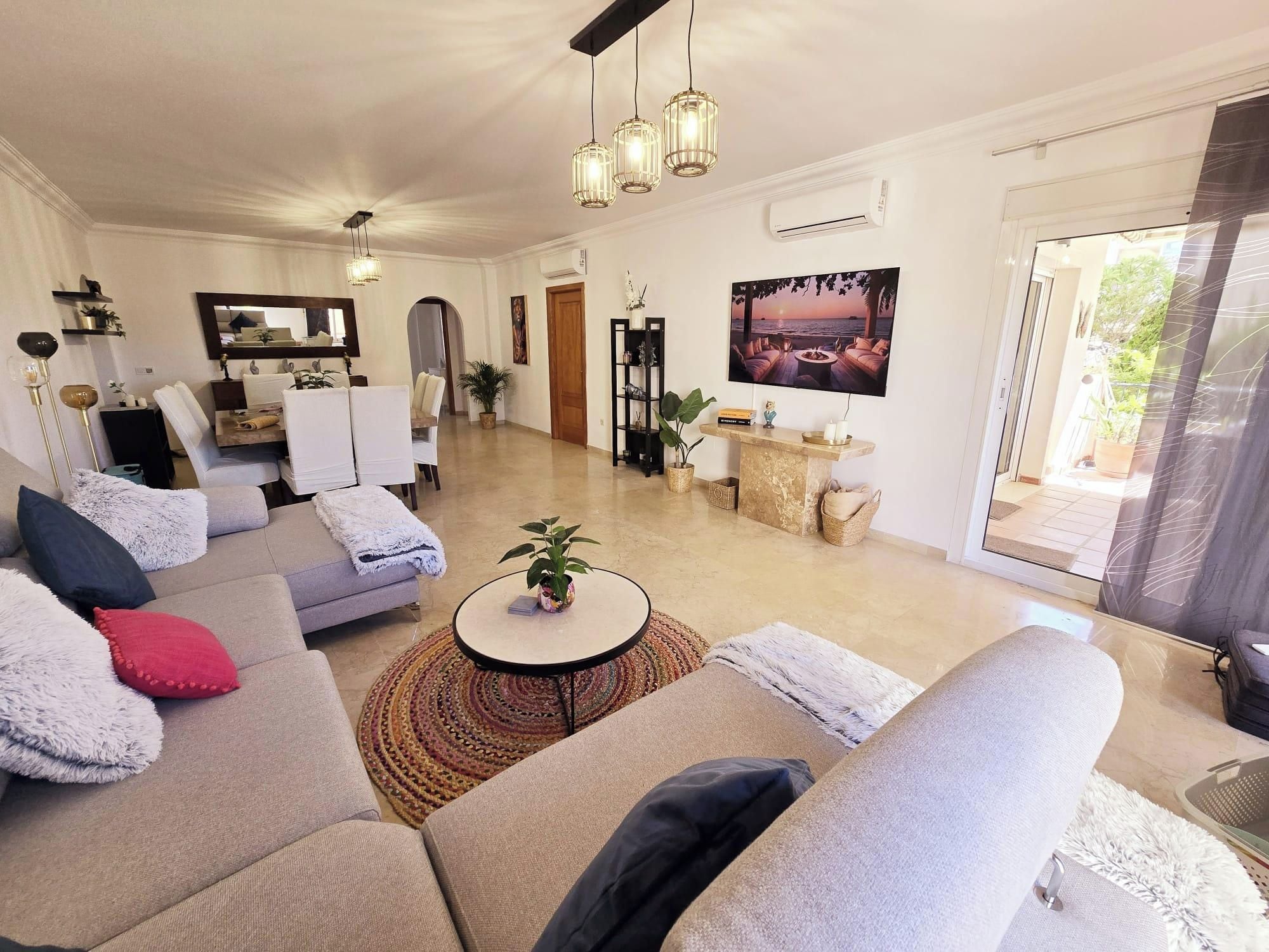 A spacious living area with a sofa, a coffee table, and a TV mounted on the wall.