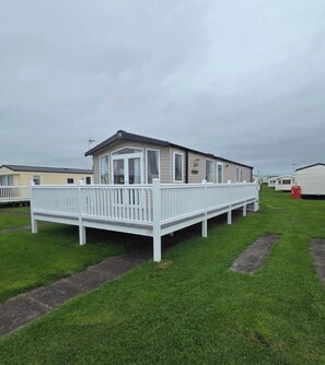 A mobile home with a deck, surrounded by other similar homes.