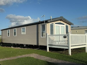 A mobile home with a porch and a fenced area.