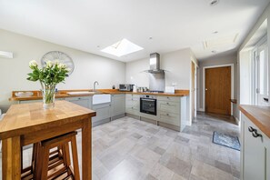 A modern kitchen with a skylight, a dining area with a wooden table, and a view of the hallway. - One Bed Bungalow Sleeps 4 - Garden - WiFi & Tv (Andover)