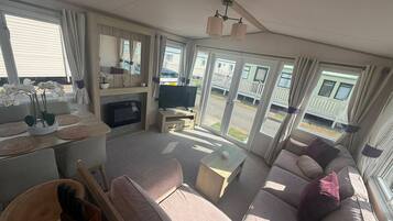 A spacious living area with a sofa, television, and a dining table with placemats.
