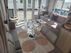 Ein gemütliches Interieur mit einer Couch, einem Esstisch mit Untersetzern und einer Orchideen-Pflanzenarrangement.