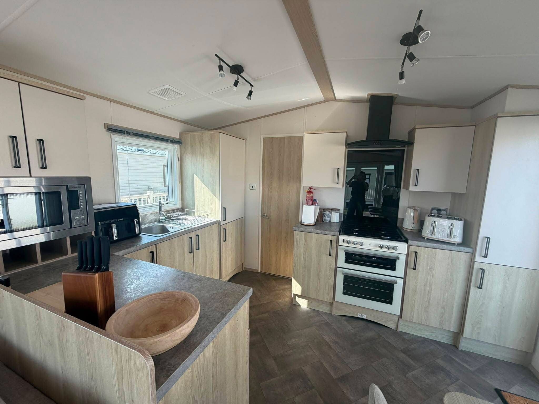 Una cocina moderna con una isla central, electrodomésticos de acero inoxidable y armarios de madera.