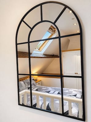A room with a skylight, a bed with a headboard, a nightstand, and a wardrobe.