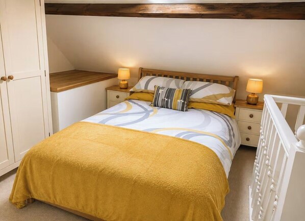 A bedroom with a bed, bedside tables, a nightstand, a crib, and a wardrobe.