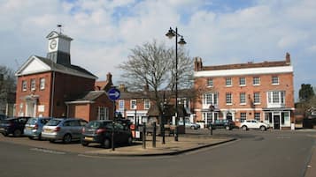 A street with parked cars, a clock tower, and a building with a sign that reads 'POISON.'