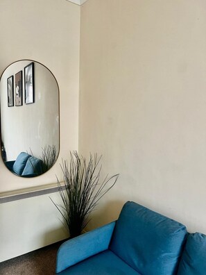 A room with a blue sofa, a large mirror, and a plant. - Apartment Sleeps 4 near Station (London)