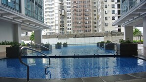 An indoor swimming pool with clear water, surrounded by a tiled floor and metal railings. - One Uptown Residence BGC City Living | Fast WiFi + Netflix (Makati City)
