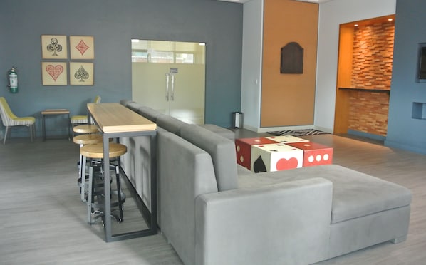 Ein stilvoller Lounge-Bereich mit grauem Sofa, Holzhockern und einem Holztisch.