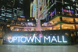 Ein Nachtblick auf das Uptown Mall mit beleuchteten Schildern und umliegenden Gebäuden.