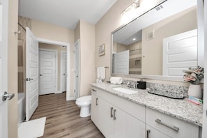 A modern bathroom with a large mirror, white fixtures, and a wooden floor. - luxury 2 kings bedrooms  2 bathrooms woodland (Montgomery)