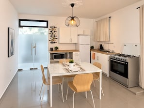 A modern kitchen with a dining area, stainless steel appliances, and a glass door leading to a balcony.