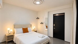 A modern hotel room with a large bed, bedside tables with lamps, a wardrobe, and a door. - SoHo Living: a stylish 2-bedroom boutique stay in the heart of Cap-Haïtien. (Cap-Haïtien)