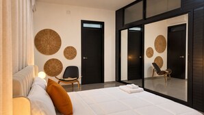A modern hotel room with a large bed, a seating area with a chair, and a wall with circular wall art. - SoHo Living: a stylish 2-bedroom boutique stay in the heart of Cap-Haïtien. (Cap-Haïtien)