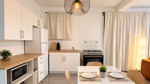 A modern kitchen with white cabinetry, a built-in oven, and a dining area with a white table and chairs. - SoHo Living: a stylish 2-bedroom boutique stay in the heart of Cap-Haïtien. (Cap-Haïtien)