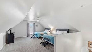 A bedroom with two beds, a ceiling fan, and a window.