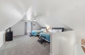 A bedroom with two beds, a ceiling fan, and a window.