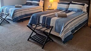 A bedroom with two beds, a ceiling fan, and a nightstand with a lamp.