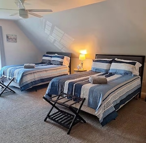 A bedroom with two beds, a ceiling fan, and a nightstand with a lamp.