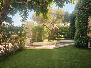 A well-maintained garden with a variety of trees and shrubs, a curved pathway, and a small water feature. - Casa Dell'Ulivo by Interhome (San Teodoro)