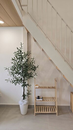 Una escalera con baranda de madera y pared blanca.