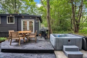 A wooden deck with a hot tub and a table with chairs. - Cozy Cabin Retreat with Hot Tub & Fire Pit. (Pocono Summit)