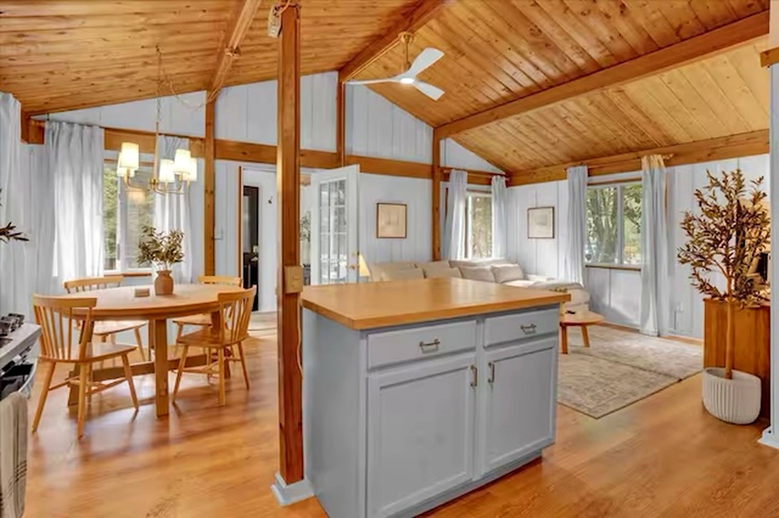 A spacious kitchen with a central island, wooden flooring, and a high ceiling with exposed beams.