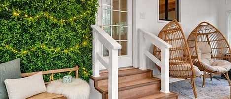 A staircase with white railings leading to a room with a green wall and wicker chairs.