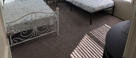 Une chambre avec deux lits, une fenêtre et un luminaire au plafond.