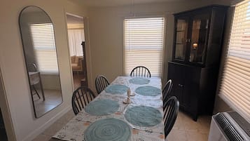 A dining area with a table set for four, a ceiling fan, and a refrigerator.