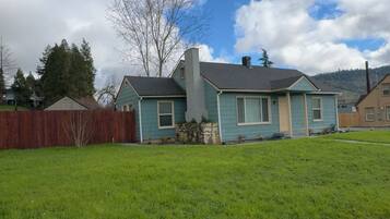 A residential house with a front yard, a wooden fence, and a clear sky.