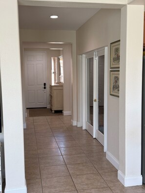 A hallway with a white door, a vanity with a mirror, and a door leading to a room. - Redford Villa- 3BR Home + 1BR Private Casita, Pool/Spa, Close to Polo (Indio)
