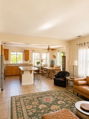 A spacious kitchen with a dining area, a living room with a sofa, and a ceiling fan. - Redford Villa- 3BR Home + 1BR Private Casita, Pool/Spa, Close to Polo (Indio)