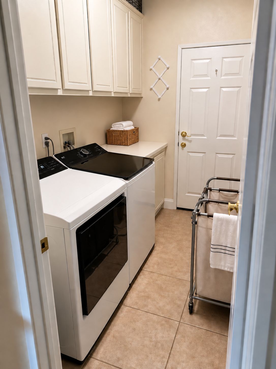 A laundry room with a washer and dryer, a basket of folded towels, and a towel rack with towels.