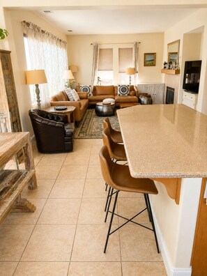 Uma sala de estar com sofá, mesa de centro e área de jantar com cadeiras e mesa.