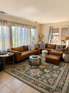 A living room with a brown leather sofa, two side tables, a round coffee table, and a patterned rug. - Redford Villa- 3BR Home + 1BR Private Casita, Pool/Spa, Close to Polo (Indio)