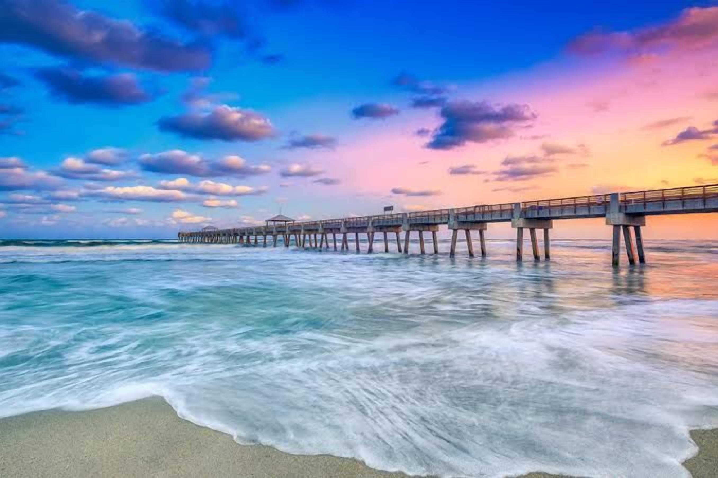 A pier extending into the ocean with waves gently lapping at the shore.
