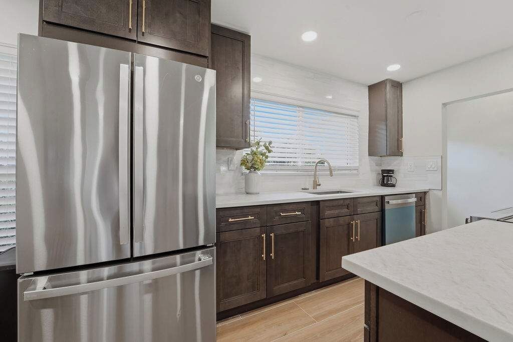 A modern kitchen with stainless steel appliances, dark wooden cabinets, and a white countertop.
