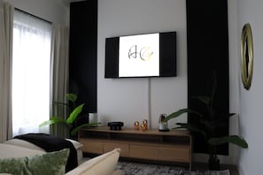 A modern living room with a flat-screen TV mounted on the wall, a wooden console table, and potted plants. - Stylish Miami Stay Near Brickell & Downtown (Miami)