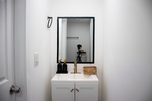A bathroom with a white sink, a mirror, and two bottles of lotion. - Stylish Miami Stay Near Brickell & Downtown (Miami)